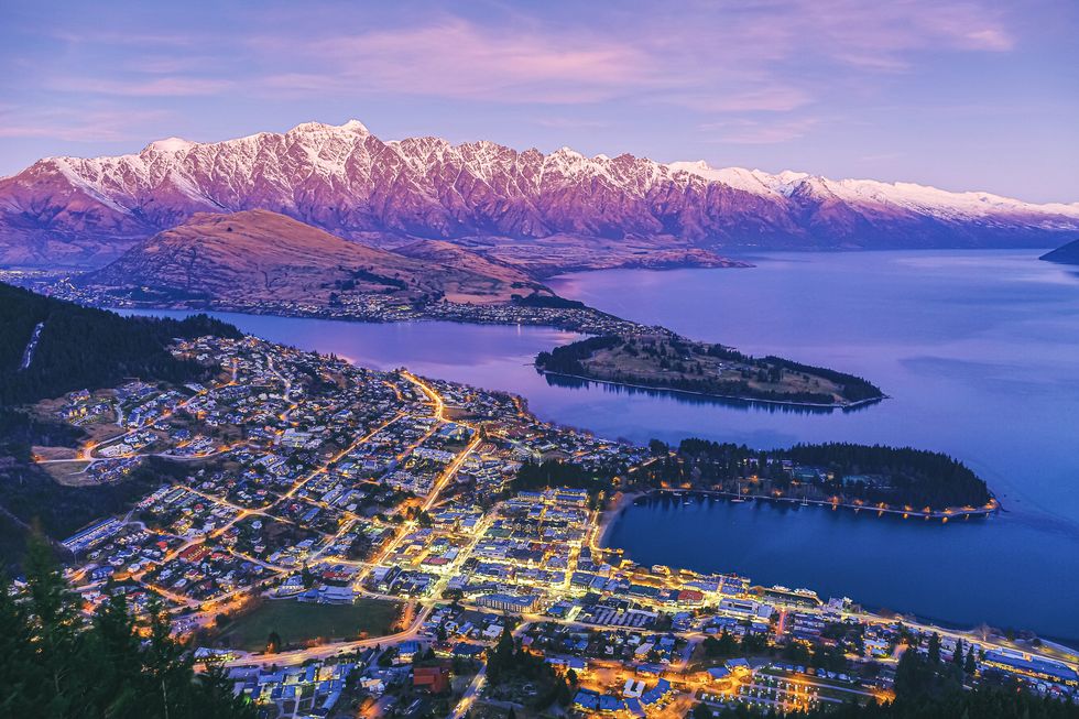 scenic dusk view of illuminated queenstown cityscape at beautiful sunset with lake wakatipu and the remarkables mountain range, queenstown, famous resort town in otago region, south island, new zealand