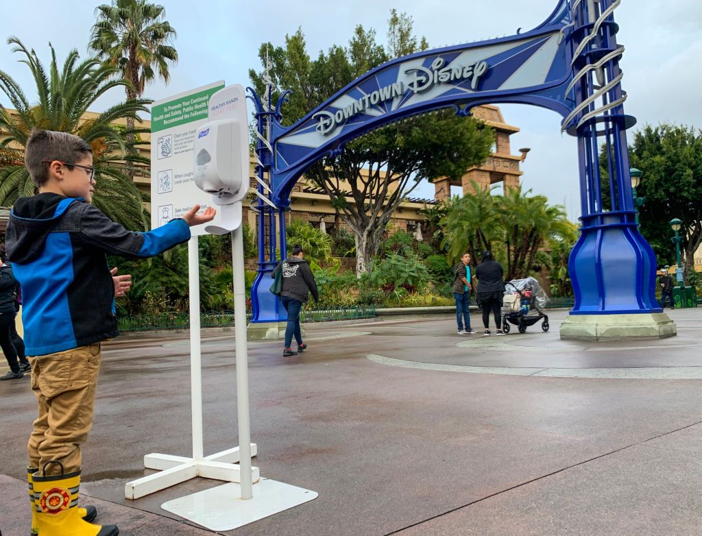 anaheim, ca   march 13 a young visitor to downtown disney uses a hand sanitizer station during the day last before disneyland closes because of the coronavirus covid 19 outbreak in anaheim, ca, on friday, march 13, 2020 photo by jeff gritchenmedianews grouporange county register via getty images