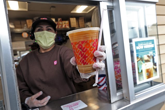 norwell, ma   march 17  a dunkin worker hands a coffee out of a drive thru window wearing gloves and a mask as the coronavirus continues to spread on march 17, 2020 in norwell, massachusetts staff photo by matt stonemedianews groupboston herald