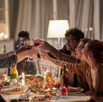group of happy young friends toasting with wine and celebrating the holiday together at the table with holiday dinner at home