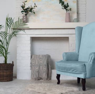 blue armchair and indoor plants and fireplace in the background classical living room furniture and potted plants