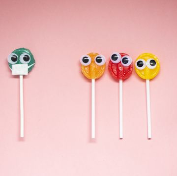 lollipop with cartoon eyes on pink colored background, social distancing concept