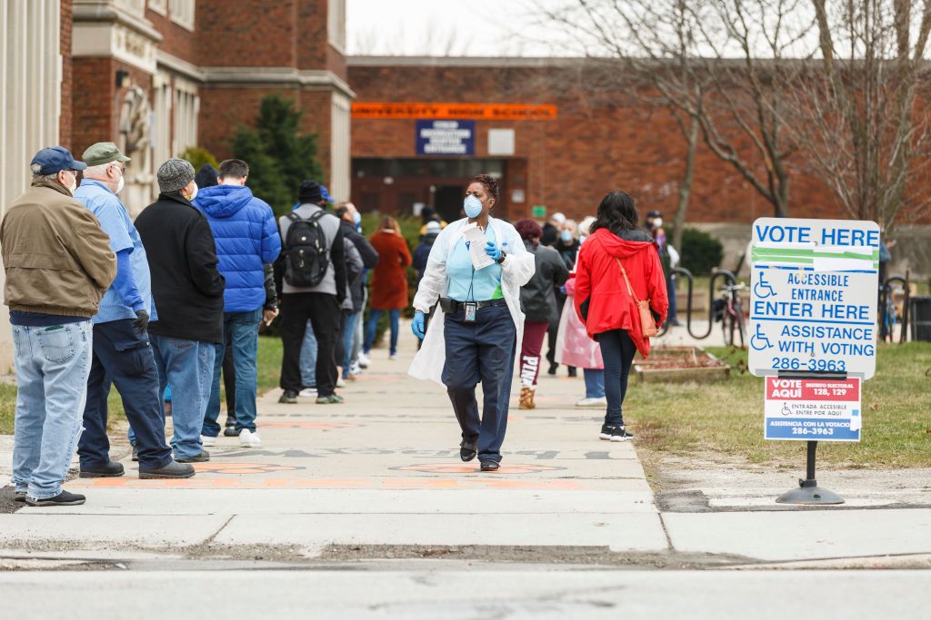 milwaukee, wi  april 7 a woman hands out surgical masks to people standing in line to vote in wisconsins spring primary election on tuesday, april 7, 2020 at riverside high school in milwaukee, wi photo by sara stathas for the washington post