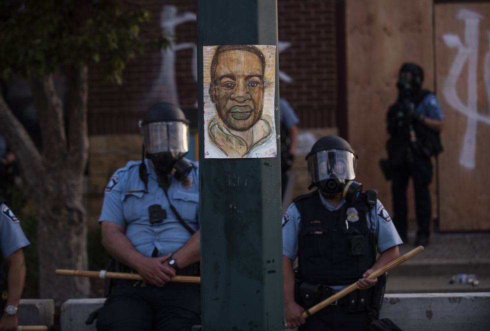 minneapolis, mn   may 27 a portrait of george floyd hangs on a street light pole as police officers stand guard at the third police precinct during a face off with a group of protesters on may 27, 2020 in minneapolis, minnesota  the station has become the site of an ongoing protest after the police killing of george floyd four minneapolis police officers have been fired after a video taken by a bystander was posted on social media showing floyd's neck being pinned to the ground by an officer as he repeatedly said, "i can‚Äôt breathe" floyd was later pronounced dead while in police custody after being transported to hennepin county medical center  photo by stephen maturengetty images