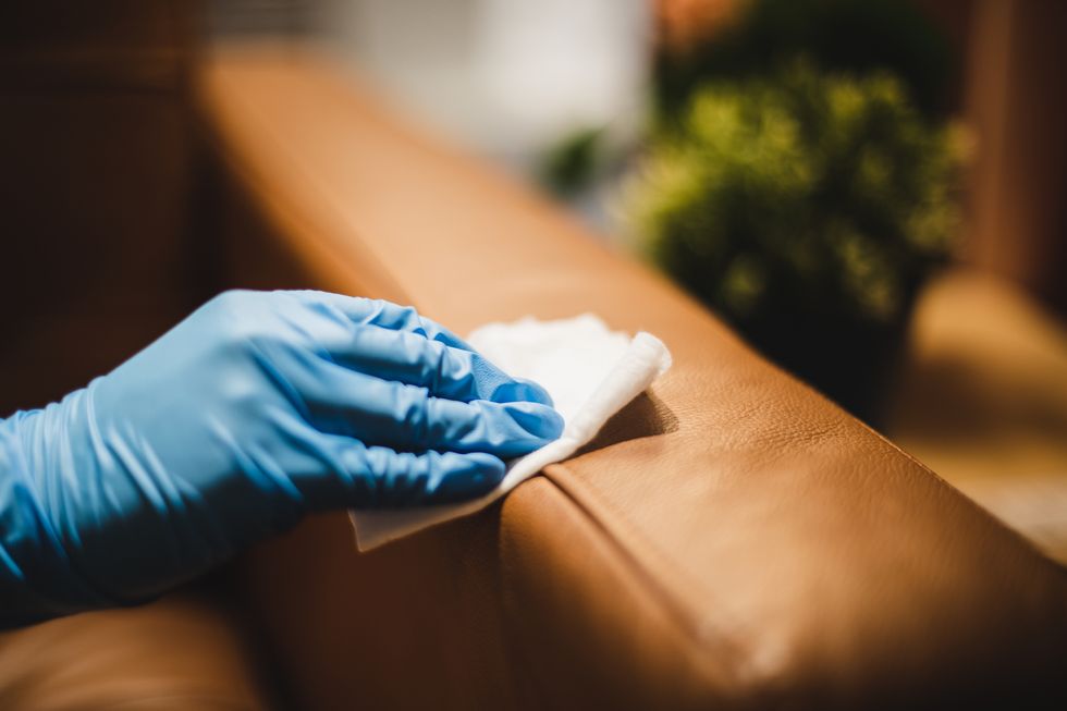 wiping down leather sofa surface using disposable wipes