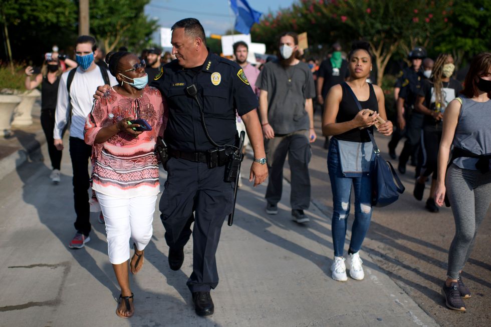 houston police chief art acevedo walks arm in arm with a woman during a justice for george floyd event in houston, texas on may 30, 2020, after george floyd, an unarmed black, died while being arrested and pinned to the ground by a minneapolis police officer   clashes broke out and major cities imposed curfews as america began another night of unrest saturday with angry demonstrators ignoring warnings from president donald trump that his government would stop violent protests over police brutality cold photo by mark felix  afp photo by mark felixafp via getty images