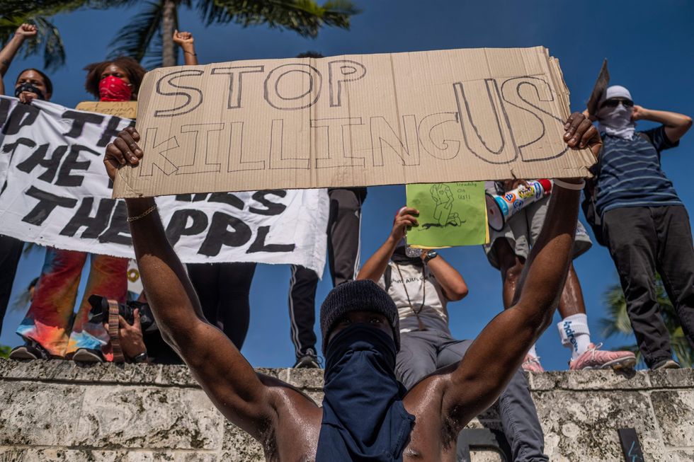topshot   protesters hold signs during a rally in response to the recent death of george floyd, an unarmed black man who died while in police custody in minneapolis, in miami, florida on may 31, 2020   thousands of national guard troops patrolled major us cities after five consecutive nights of protests over racism and police brutality that boiled over into arson and looting, sending shock waves through the country the death monday of an unarmed black man, george floyd, at the hands of police in minneapolis ignited this latest wave of outrage in the us over law enforcements repeated use of lethal force against african americans    this one like others before captured on cellphone video photo by ricardo arduengo  afp photo by ricardo arduengoafp via getty images