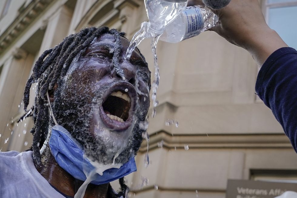 washington, dc   june 01 a demonstrator is doused with water and milk after being hit with pepper spray from law enforcement during a protest on june 1, 2020 in downtown washington, dc protests and riots continue in cities across america following the death of george floyd, who died after being restrained by minneapolis police officer derek chauvin chauvin, 44, was charged last friday with third degree murder and second degree manslaughter photo by drew angerergetty images