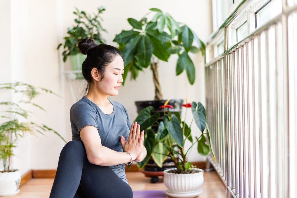 asian young woman practicing yoga in the living room