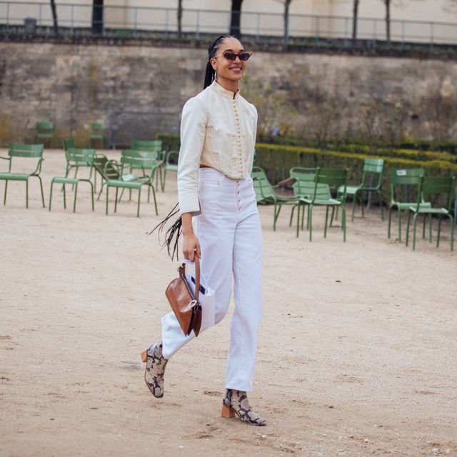 paris, france   february 25 model indira scott wears a cat eye sunglasses, vintage style cream button up top , white jeans, a small brown bag, and python boots after the dior show during paris fashion week fallwinter 2020 on february 25, 2020 in paris, france photo by melodie jenggetty images