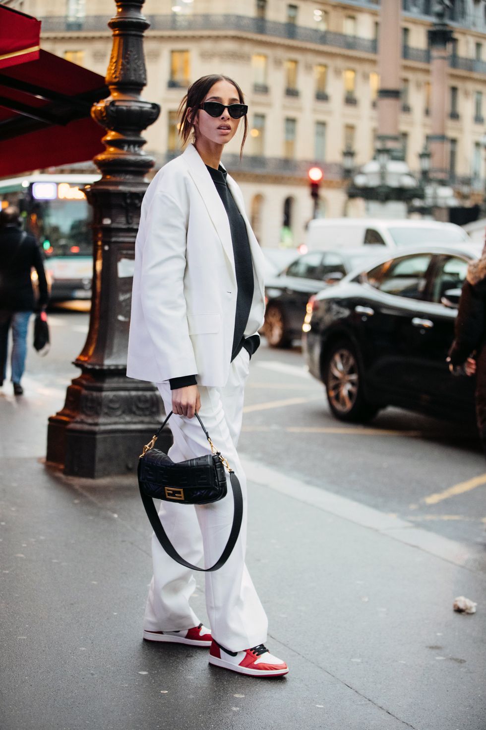 paris, france   february 28 model yasmin wijnaldum wears black sunglasses, a white matching suit jacket and pants, black top, black leather fendi baguette bag, and red and white nike jordan sneakers after the redemption show during paris fashion week fallwinter 2020 on february 28, 2020 in paris, france photo by melodie jenggetty images