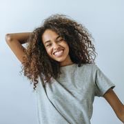 portrait of woman with afro hair smiling with white wall background