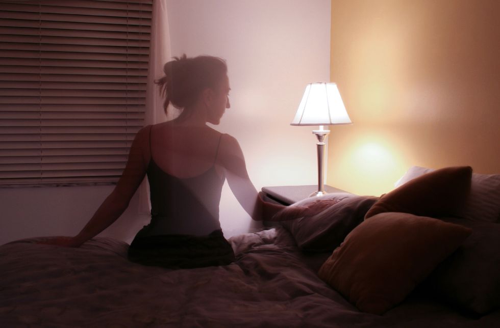 ghosted woman touching pillow in bedroom