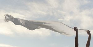 woman holds a white scarf that flies in the sky freedom concept