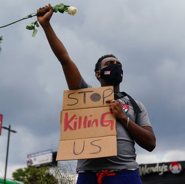 topshot   a man holds a sign and a white rose in his fist while facing traffic outside a burned wendys restaurant on the second day following the police shooting death of rayshard brooks in the restaurant parking lot june 14, 2020, in atlanta, georgia   the fatal shooting of a black man by a white police officer, this time in atlanta, georgia, poured more fuel june 14, 2020 on a raging us debate over racism after another round of street protests and the resignation of the city's police chief a wendy's restaurant where 27 year old rayshard brooks was killed was set on fire june 13, 2020 and hundreds of people marched to protest the killing photo by elijah nouvelage  afp photo by elijah nouvelageafp via getty images