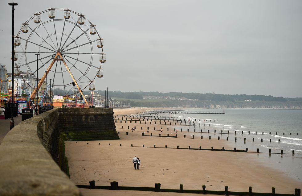 people walk along an empty beach in bridlington on the north east coast of england on june 15, 2020, as some non essential retailers reopen from their coronavirus shutdown photo by oli scarff  afp photo by oli scarffafp via getty images