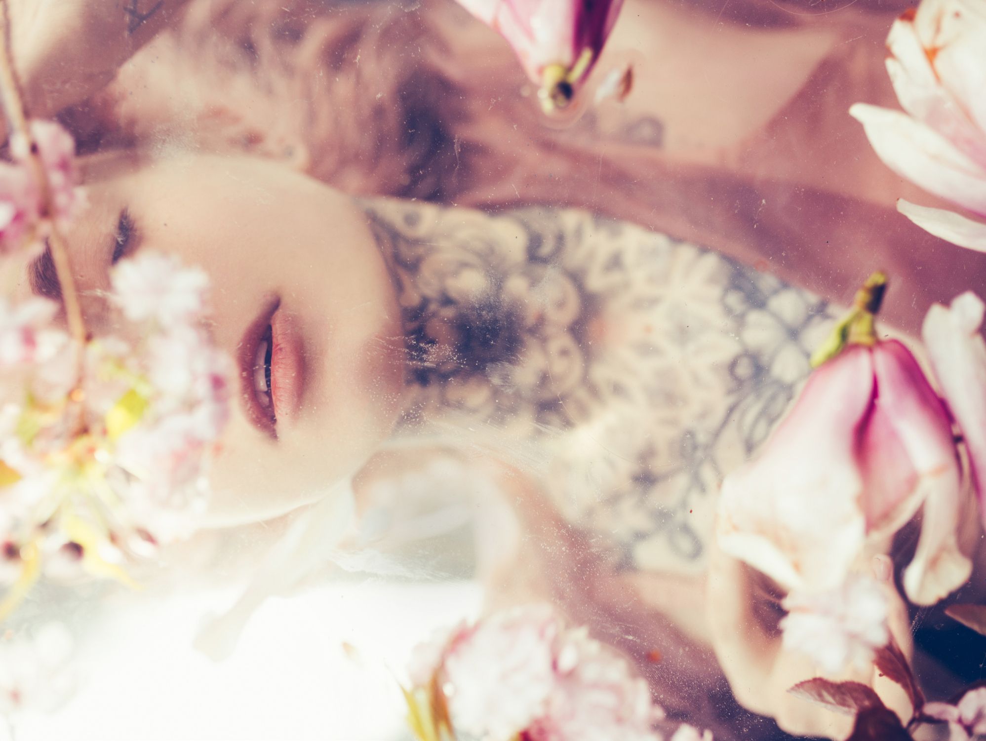 portrait of young beautiful woman posing underwater with pink flowers