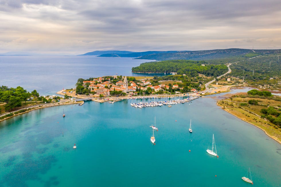 idyllic landscape with the aerial view of a coastal old town, boats in sea and a marina, cres island, croatia
