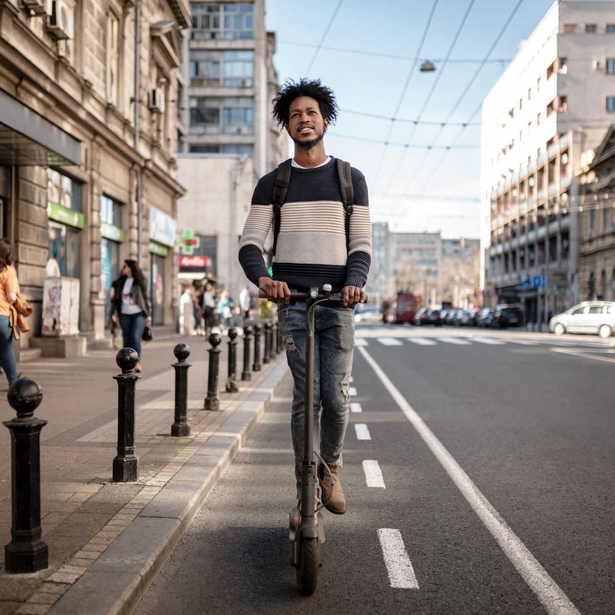 front view of a young african american man exploring the city using a scooter