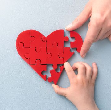 woman and child arranges red heart shape puzzles symbol of helping others