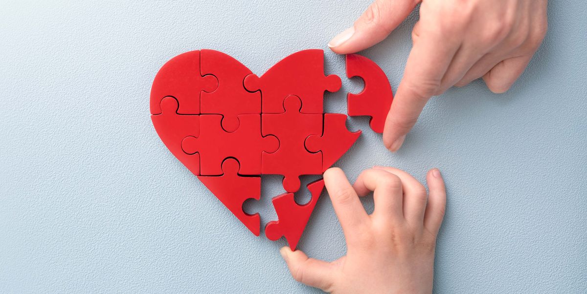woman and child arranges red heart shape puzzles symbol of helping others