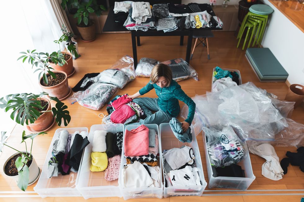 a woman organizes clothes in living room of her home