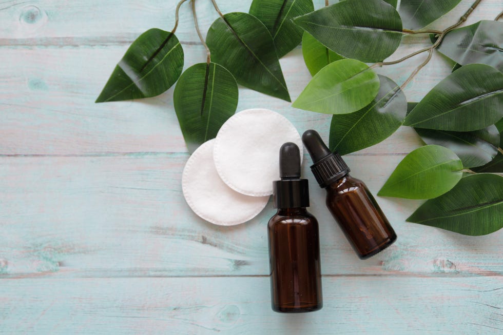 natural essential oils and green leaves on blue background