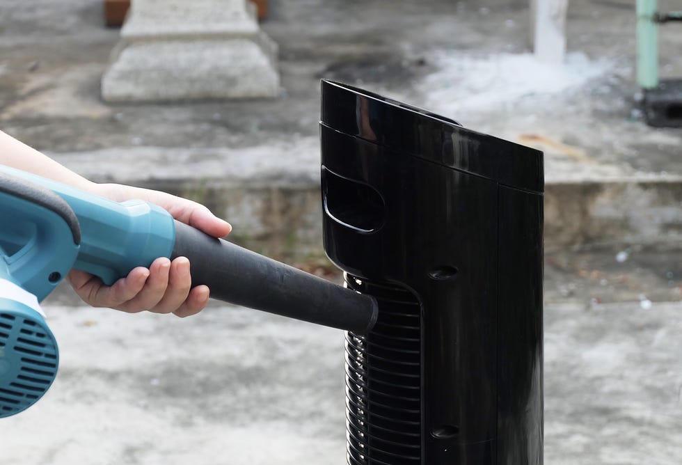 person using the air blower to clean a tower fan, use to remove dust from the electrical machine.