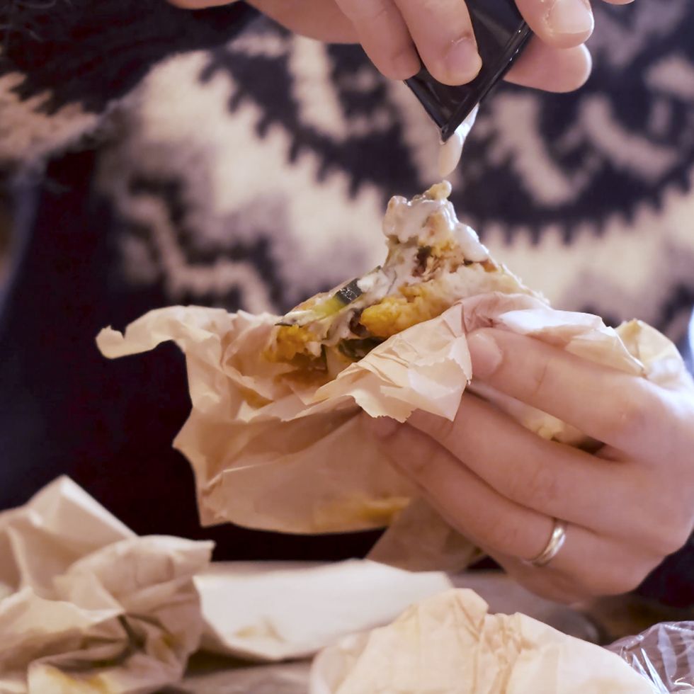 man pouring tahini onto his falafel sandwich in a restaurant for lunch  slow motion 4k video