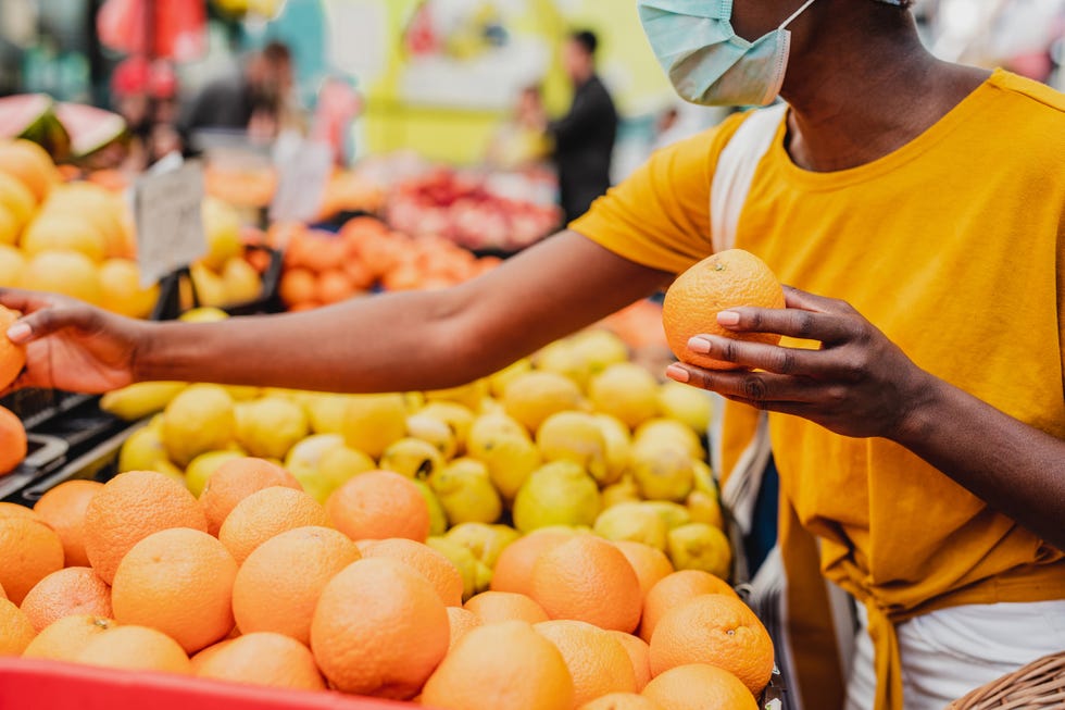 african american woman wearing a protective mask while buying groceries at the market