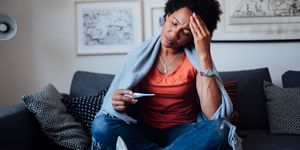 worried african american woman sitting at home while being sick
