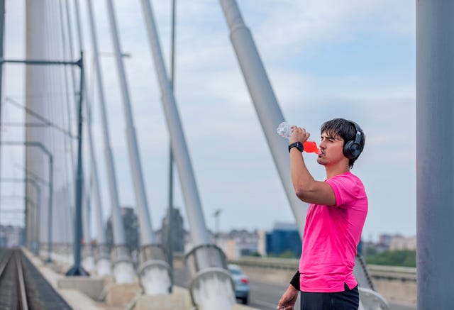 attractive athlete drinks a shake on a bridge