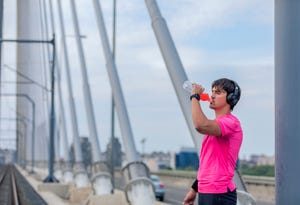 attractive athlete drinks a shake on a bridge