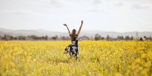 mujer saltando en un campo de flores