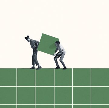 full length of young woman and man carrying large green block on grid against white background