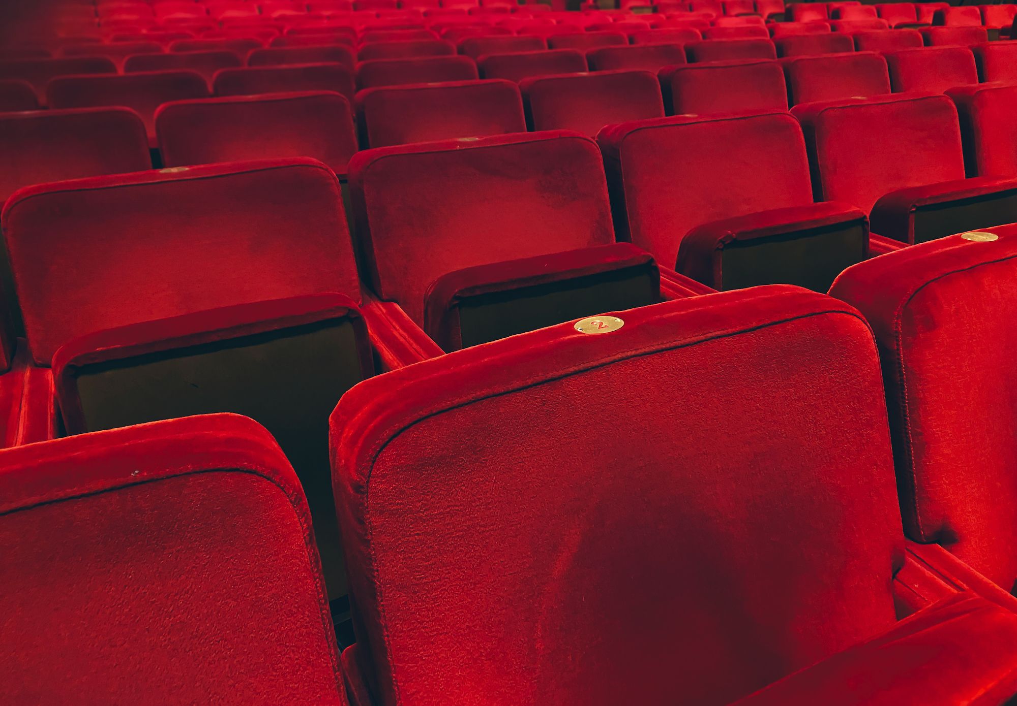 empty red velvet armchairs illuminated inside a concert hall