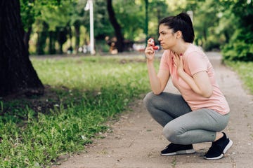 vrouw gebruikt astma inhaler na hardlopen in het park