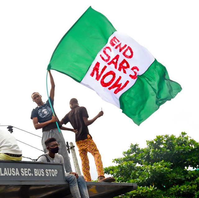 a protester waves the nigerian national flag while gathering with other protesters to barricade the lagos   ibadan expressway, the oldest highway and major link to all parts of the country, during a demonstration to campaign against police brutality and scrapping of the special anti robbery squad sars in lagos, on october 15, 2020   nigerian youth continued to march against police violence in several major cities across the country on october 15, 2020, despite further attacks on processions by men armed with sticks and machetes