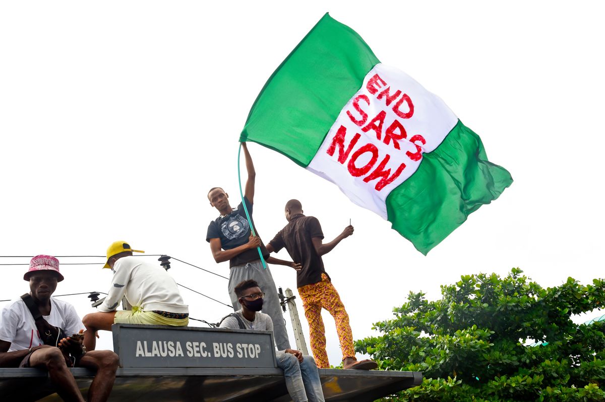 a protester waves the nigerian national flag while gathering with other protesters to barricade the lagos   ibadan expressway, the oldest highway and major link to all parts of the country, during a demonstration to campaign against police brutality and scrapping of the special anti robbery squad sars in lagos, on october 15, 2020   nigerian youth continued to march against police violence in several major cities across the country on october 15, 2020, despite further attacks on processions by men armed with sticks and machetes