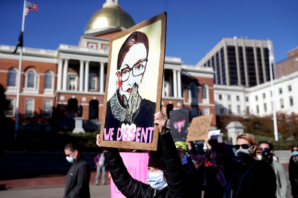 boston, ma october 17 a protester holds a poster with ruth bader ginsburg's face and text reading "we dissent" as roughly 1,000 demonstrators take over the streets around boston common in a show of resistance to president trump in boston on oct 17, 2020 the demonstrations were planned by the womens march organization that staged marches around the world the day after trumps inauguration to protest the confirmation of supreme court nominee amy coney barrett and to rally voter opposition to trumps reelection photo by jonathan wiggsthe boston globe via getty images