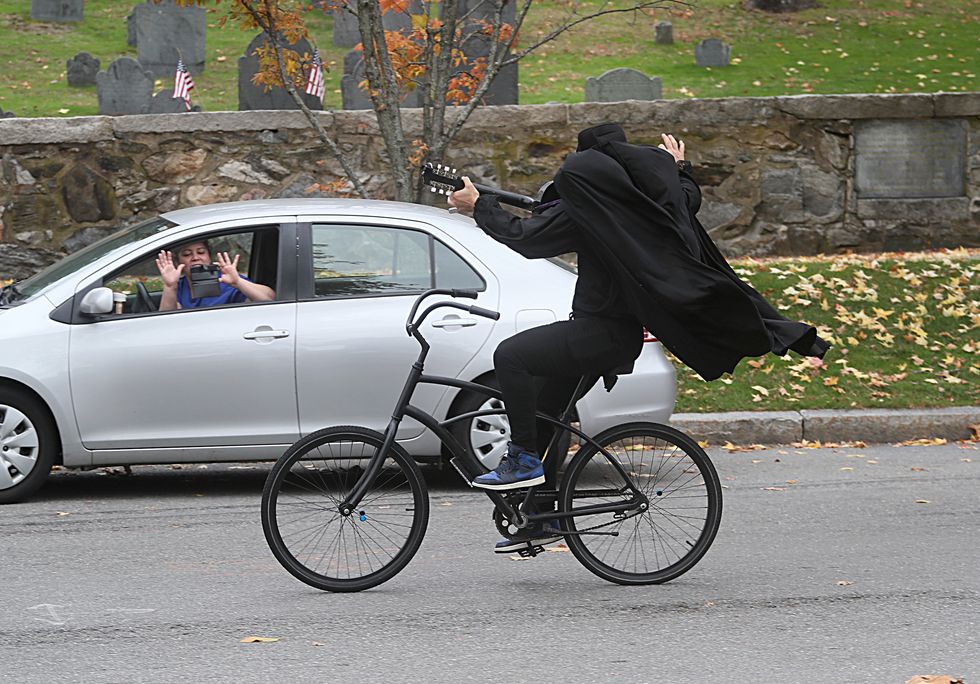 slam dunkle the headless horseman musical cyclist riding and playing in concord, massachusetts, waving at someone taking a picture in their car