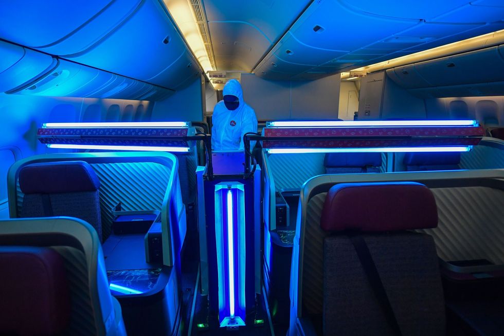 Een medewerker van de Chileense luchtvaartmaatschappij LATAM ziet begin 2020 toe op het werk van een robot die een vliegtuig met UVClicht ontsmet Als de robots op de juiste manier worden gebruikt kan het UVlicht virussen doden waaronder ook het coronavirus