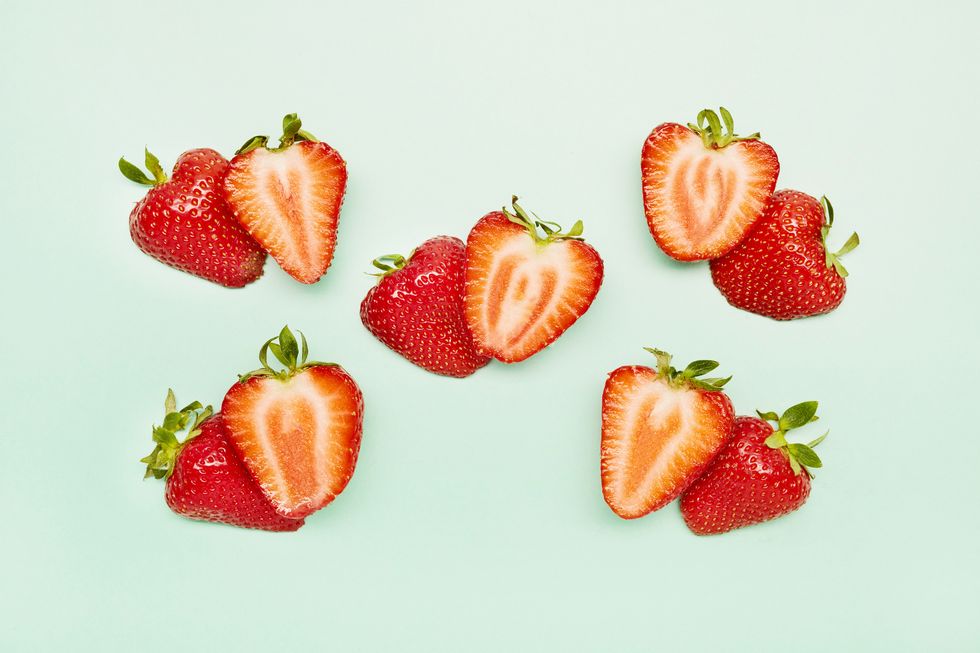 a group of sliced strawberries against a turquoise background