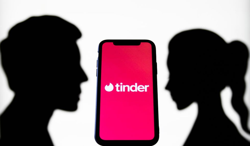 tinder logo displayed on a phone screen is seen with paper silhouettes looking like a man and a woman in this illustration photo taken in krakow, poland on july 31, 2021 photo by jakub porzyckinurphoto via getty images