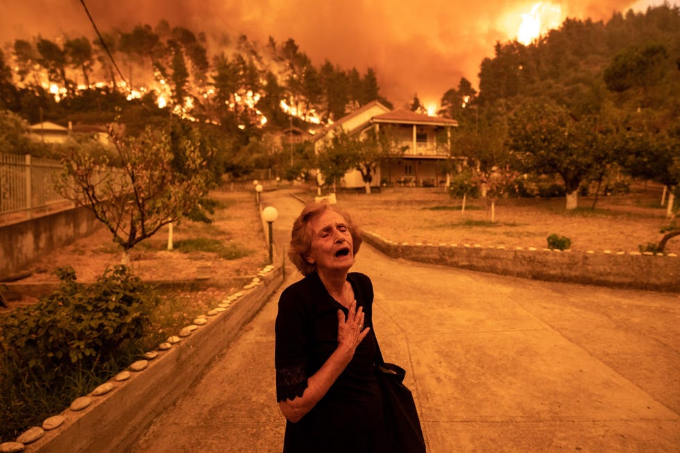 Residents Evacuate Greek Island Hit By Wildfires Een oudere bewoonster van Evia het op een na grootste eiland van Griekenland toont op 8 augustus haar verdriet terwijl een bosbrand haar huis nadert De branden woedden op zon grote schaal op het eiland dat duizenden inwoners per boot moesten worden gevacueerd