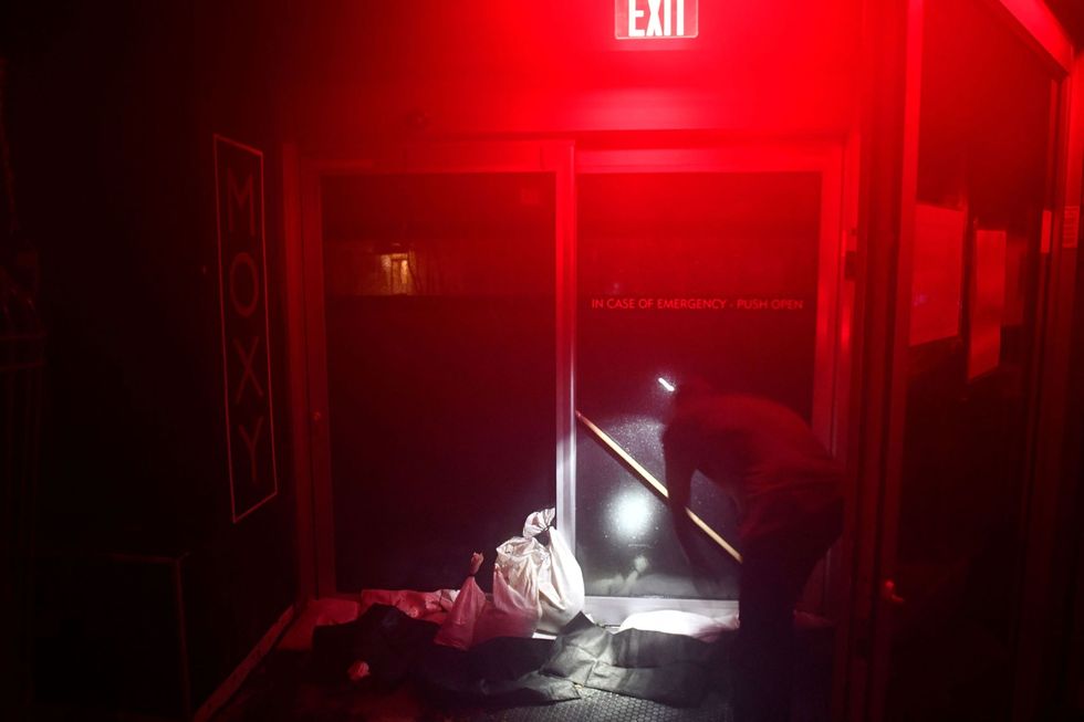 Een werknemer van een hotel stut een deur om te voorkomen dat hij door de harde wind openwaait Het hotel in New Orleans kwam tijdens hurricane Ida zonder stroom te zitten Volgens het ministerie van Binnenlandse Veiligheid trof de storm vooral de zuidelijke staat Louisiana