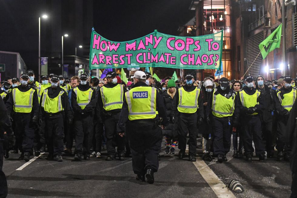 glasgow, scotland   november 03 police officers escort an extinction rebellion protest outside the cop26 summit as a banner is seen reading how many cops to arrest climate chaos on november 3, 2021 in glasgow, united kingdom as world leaders meet to discuss climate change at the cop26 summit, many climate action groups have taken to the streets to protest for real progress to be made by governments to reduce carbon emissions, clean up the oceans, reduce fossil fuel use and other issues relating to global heating photo by peter summersgetty images