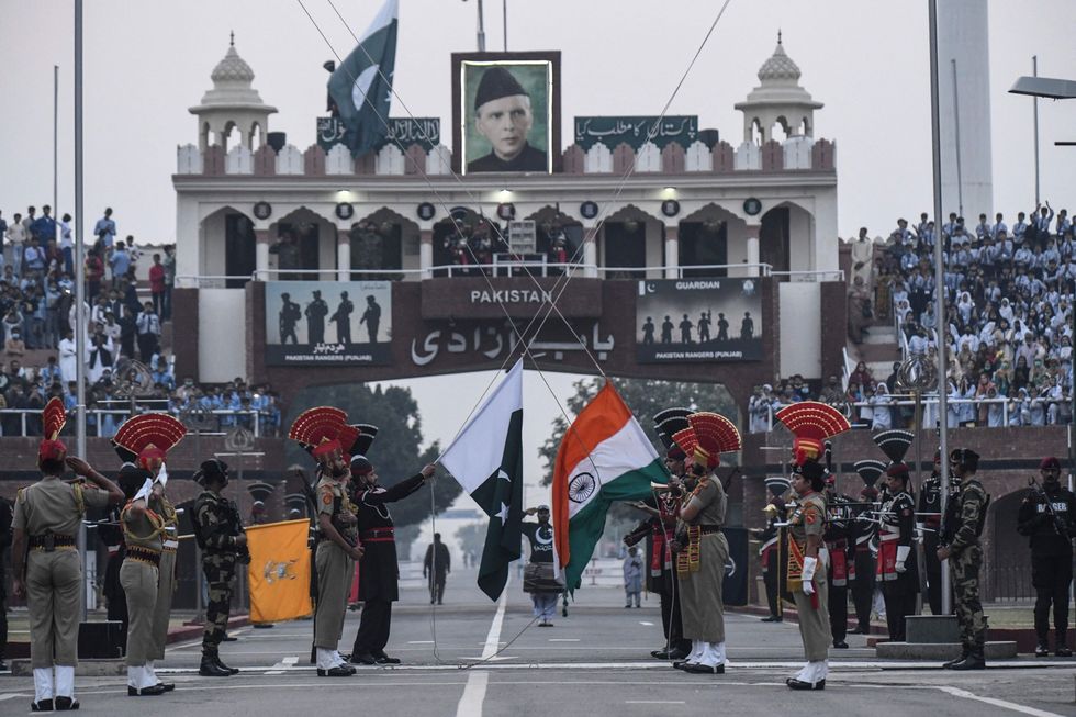 De Border Security Force van India en Pakistaanse Rangers in het zwart laten hun vlaggen zakken tijdens de dagelijkse Beating Retreat aan de grens tussen Wagah en Attari op 15 november 2021 Deze ceremonie is een oude Britse traditie om patrouillerende troepen aan het einde van de dag terug te roepen