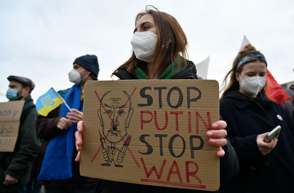 a woman holds a poster asking to stop putin   stop war as demonstrators protest against russias invasion of ukraine on february 24, 2022 in front of the brandenburg gate in berlin photo by john macdougall  afp photo by john macdougallafp via getty images