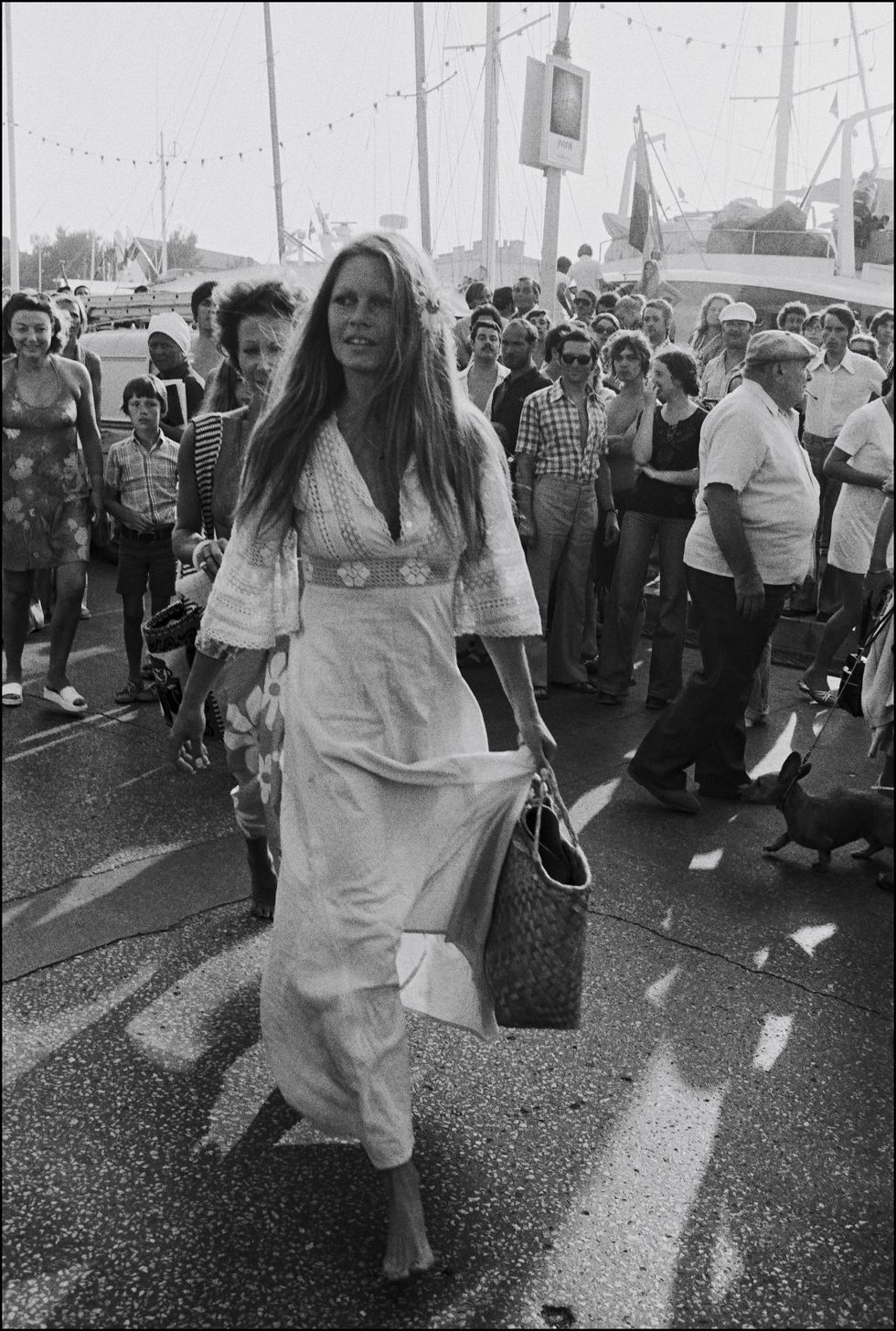 Brigitte Bardot por la calle con vestido blanco con encajes y descalza